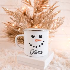 a snowman mug sitting on top of a white box next to a christmas tree