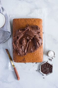 a cake with chocolate frosting sitting on top of a table next to some spoons