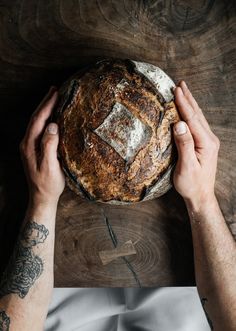 two hands holding a loaf of bread on top of a wooden table with the words ambrosia above it