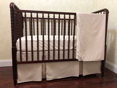 a baby crib with white sheets on it