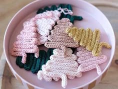 crocheted baby mittens are in a pink bowl