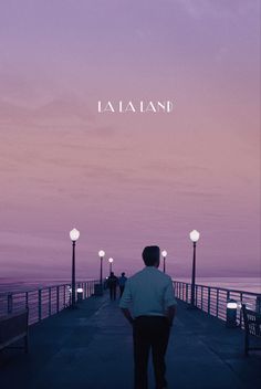 a man standing on top of a pier next to the ocean under a purple sky