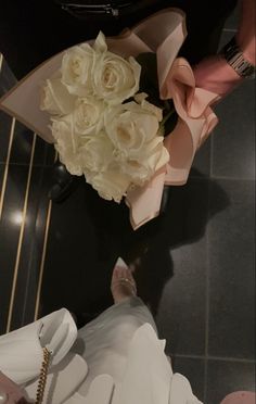 a bouquet of white flowers sitting on top of a black table next to a pair of shoes