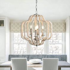 a chandelier hanging from the ceiling in a dining room with white walls and chairs