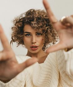 a woman with curly hair making the vulcan sign