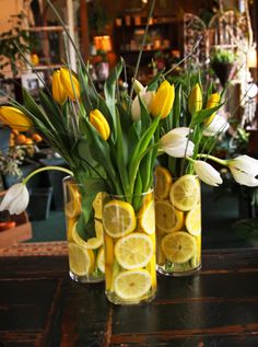 three vases filled with lemon slices and tulips on top of a table