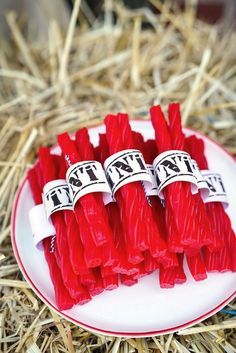 small red candles are on a plate in the hay