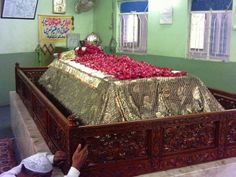 a man kneeling in front of a large bed covered with red flowers on it's side