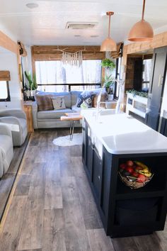 a kitchen and living room area in a mobile home with wood flooring, white counter tops and black cabinets