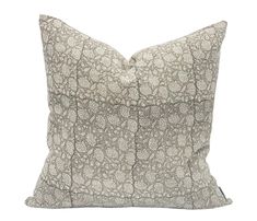 a gray and white pillow with an intricate design on the front, sitting on a white background