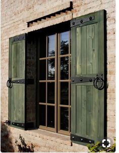 an open window with green shutters on a brick building