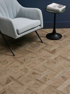 a white chair sitting next to a table on top of a hard wood flooring