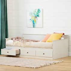 a white daybed with drawers underneath it in a living room next to a window