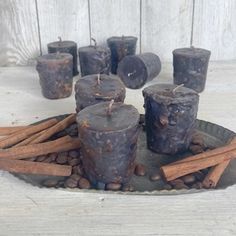 several candles and cinnamon sticks on a tray