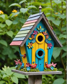 a colorful birdhouse with flowers on the roof