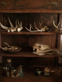 an old wooden shelf with antlers and other items on it's shelves in a room