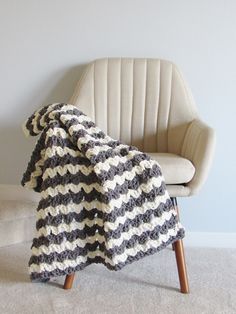 a chair with a blanket on it sitting in front of a white wall and floor