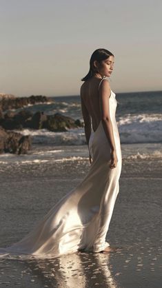 a woman in a white dress standing on the beach