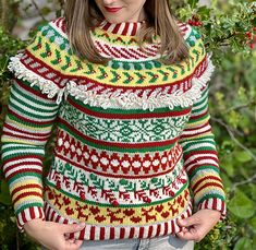 a woman standing in front of some trees wearing a sweater with an ugly pattern on it