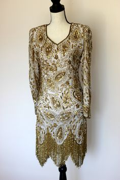 "Beautiful Gunit Flapper Dress with Gold beads and sequins throughout. Excellent condition! Long flowy gold beaded fringe. This one is a true head turner!! Zipper in the back Measuring: 36\" long 34\" bust 28\" waist 34\" hip 23\" sleeve Beautiful! in every way!! Pet free/ smoke free Enjoy!" Gold Flapper Dress For Party, Glamorous Gold Flapper Dress For Party Season, Glamorous Gold Flapper Dress For Evening, Glamorous Gold Flapper Dress For Cocktail, Gold Party Dress With Rhinestone Fringe, Elegant Gold Dress With Rhinestone Fringe, Vintage Gold Flapper Dress For Party, Gold Sequined Flapper Dress For Party Season, Fitted Embellished Flapper Dress For Festive Occasions