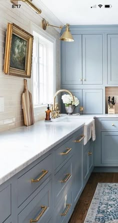 a kitchen with blue cabinets and gold pulls on the handles, an area rug in front of the sink