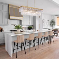 a kitchen with an island and bar stools in the center, surrounded by gray cabinets