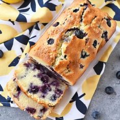 a loaf of blueberry bread sitting on top of a yellow and black cloth next to lemons