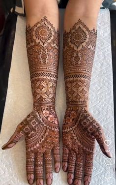 two hands with henna tattoos on them, one is showing off the intricate design