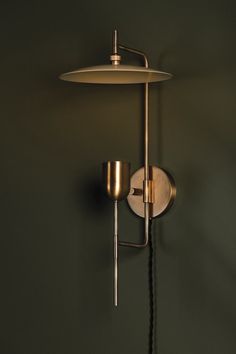 a wall mounted lamp on the side of a green wall next to a light fixture