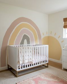 a baby's room with a rainbow painted on the wall