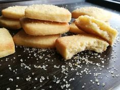 some sugary cookies are on a wooden table with sprinkles around them