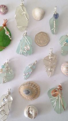 a collection of sea glass and seashells on a white surface with a green leaf