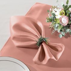 a pink table cloth with a flower on it and a white plate next to it