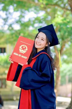 a woman in graduation gown holding up a red book