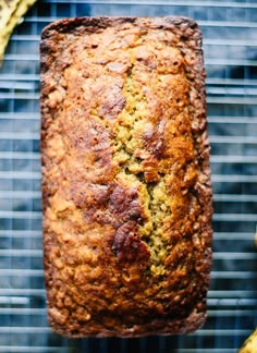 a loaf of banana bread sitting on top of a cooling rack next to some bananas