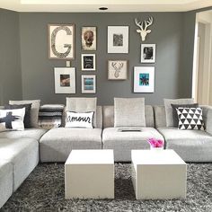 a living room with gray walls and pictures on the wall above the sectional couches