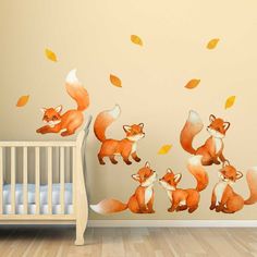 a baby's room with a wall decal that has foxes and leaves on it