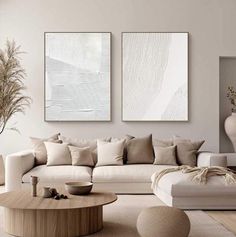 a living room with two paintings on the wall and a white couch in front of it