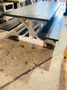 a wooden table with benches sitting on top of it in a room filled with other furniture