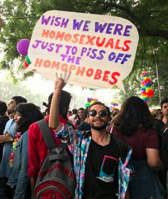 a man holding up a sign that says wish we were homosexuals just to piss off homophobiaes