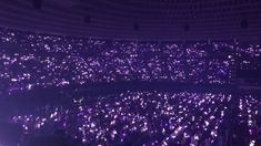 a large room filled with lots of purple lights and people standing in the middle of it