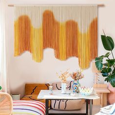 a living room filled with furniture next to a wall covered in yellow string hangings