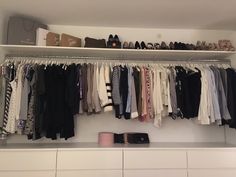 a closet with clothes and shoes hanging on the wall next to a shelf filled with other items