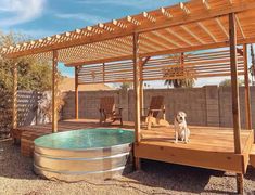 a dog is sitting on the deck next to an outdoor hot tub and gazebo