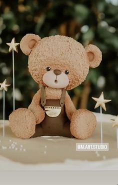 a brown teddy bear sitting on top of a cake covered in icing and stars