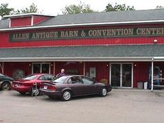 the front of an antique barn and convention center with cars parked in front of it