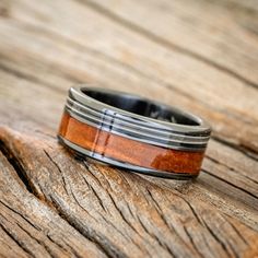 a wedding band that has been made with wood and silver inlays is sitting on a wooden surface