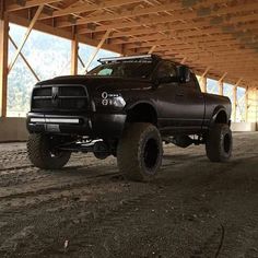 a large black truck parked under a wooden structure