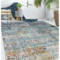 an area rug with blue, yellow and orange colors in the middle is shown next to a plant