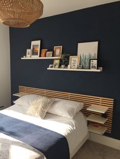 a bedroom with blue walls and pictures on the wall above the bed, along with bookshelves